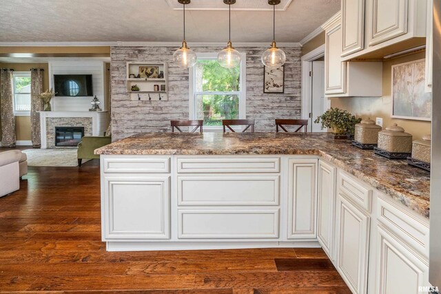 213 Texas Ave, Carterville, IL 62918 - kitchen featuring a peninsula, dark wood-type flooring, a fireplace, crown molding, and open floor plan