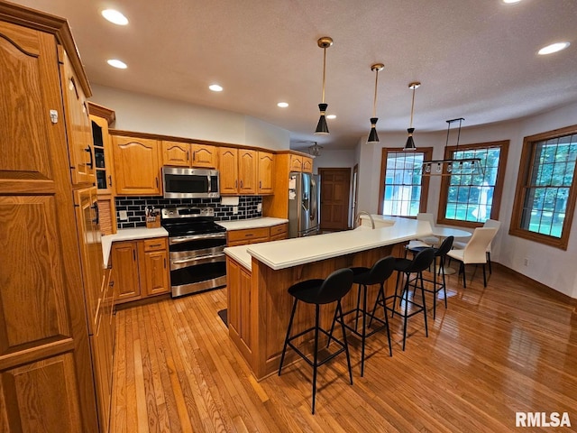 9 Fawn Dr, Fairfield, IL 62837 - kitchen featuring stainless steel appliances, brown cabinetry, light wood finished floors, recessed lighting, and tasteful backsplash