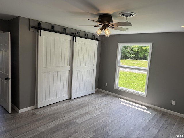 6984 Washington St, Mulkeytown, IL 62865 - unfurnished bedroom featuring a barn door, baseboards, wood finished floors, and a ceiling fan