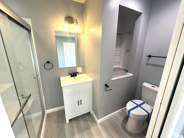 1206 E 2nd St, Centralia, IL 62801 - bathroom featuring wood finished floors, toilet, a shower stall, vanity, and baseboards