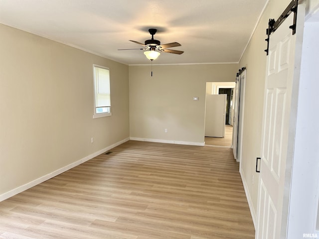 518 Noleman St, Centralia, IL 62801 - empty room featuring a barn door, ornamental molding, baseboards, a ceiling fan, and light wood-type flooring