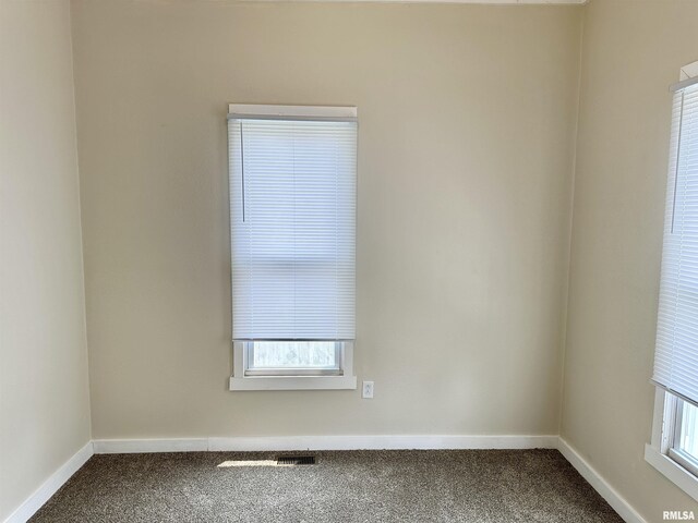 518 Noleman St, Centralia, IL 62801 - empty room featuring dark colored carpet, plenty of natural light, and baseboards