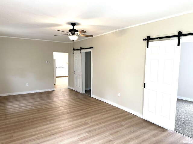 518 Noleman St, Centralia, IL 62801 - spare room featuring a barn door, ceiling fan, baseboards, light wood-type flooring, and crown molding
