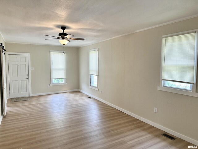 518 Noleman St, Centralia, IL 62801 - spare room with healthy amount of natural light, a barn door, a ceiling fan, light wood-type flooring, and ornamental molding