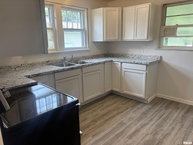 709 S Virginia St, Marion, IL 62959 - kitchen featuring black / electric stove, white cabinets, light wood finished floors, baseboards, and a sink