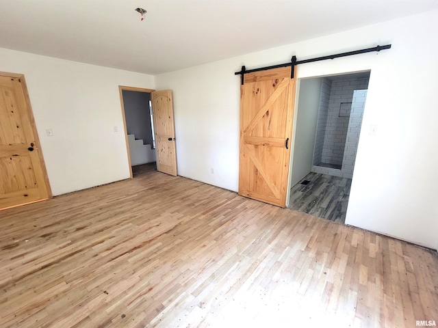 7324 State Route 161st Ext, Iuka, IL 62849 - unfurnished bedroom with light wood-style floors, a barn door, and ensuite bathroom