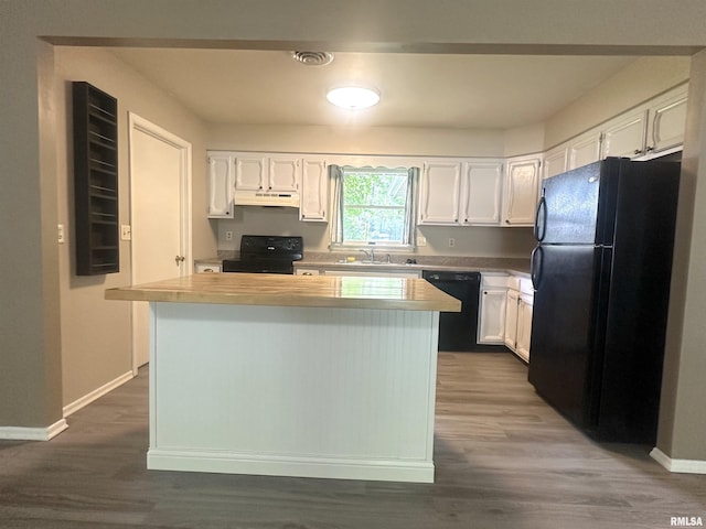 1008 N Norwest Ln, Carbondale, IL 62901 - kitchen with black appliances, under cabinet range hood, white cabinetry, light countertops, and a kitchen island