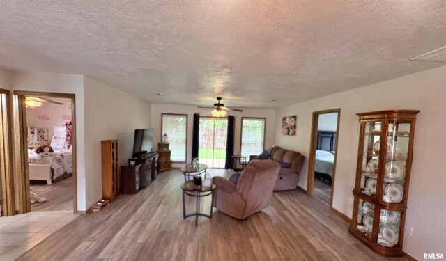 112 Townhouse Dr, Carterville, IL 62918 - living area featuring a textured ceiling, ceiling fan, light wood finished floors, and baseboards