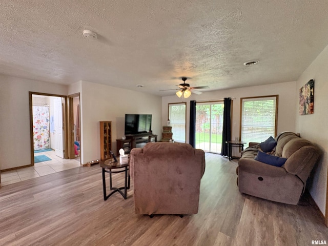 112 Townhouse Dr, Carterville, IL 62918 - living room featuring a textured ceiling, light wood-type flooring, a ceiling fan, and baseboards