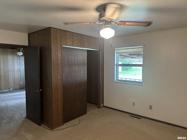 705 Terrace Dr, Duquoin, IL 62832 - unfurnished bedroom featuring light carpet, wooden walls, a baseboard radiator, ceiling fan, and a closet