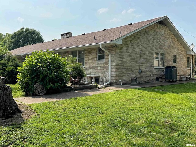 1011 W Goodall St, Marion, IL 62959 - rear view of property featuring stone siding, central air condition unit, a yard, a patio area, and a chimney