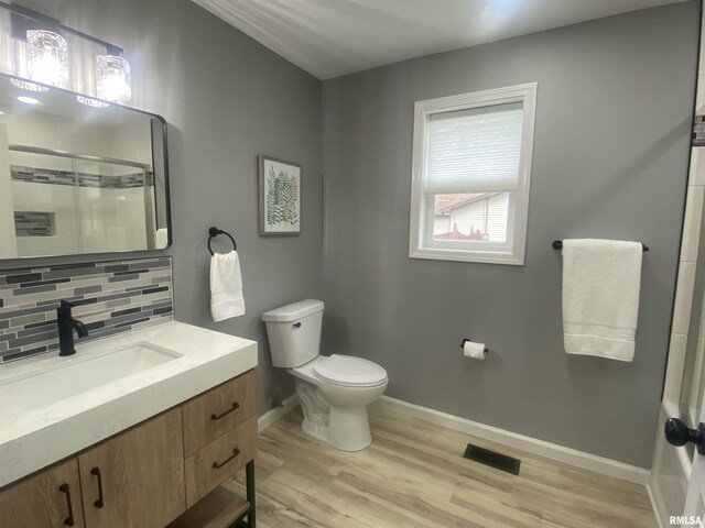 421 N 10th St, Benton, IL 62812 - bathroom with vanity, toilet, decorative backsplash, baseboards, and wood finished floors