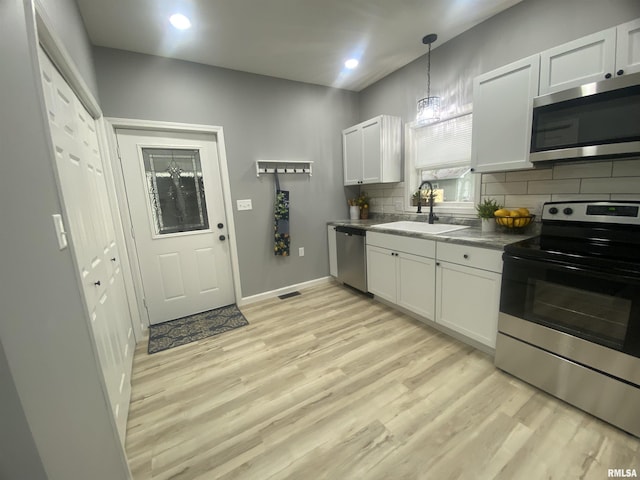 421 N 10th St, Benton, IL 62812 - kitchen with appliances with stainless steel finishes, a sink, backsplash, light wood-style flooring, and dark countertops