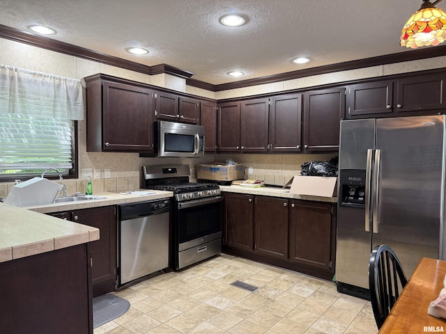 113 E 21st St, Metropolis, IL 62960 - kitchen featuring stainless steel appliances, ornamental molding, dark brown cabinetry, a sink, and a textured ceiling