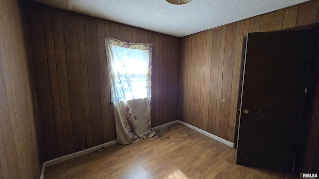 101 Diamond St, Mound City, IL 62963 - unfurnished room with light wood-style floors, wooden walls, a textured ceiling, and baseboards