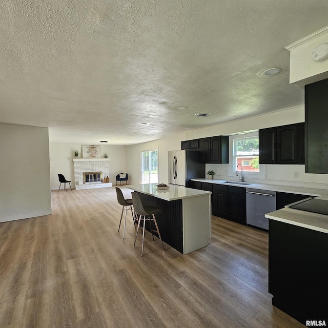 15074 N Mccauley Ln, Mount Vernon, IL 62864 - kitchen with stainless steel appliances, a sink, a center island, a textured ceiling, and light wood-type flooring