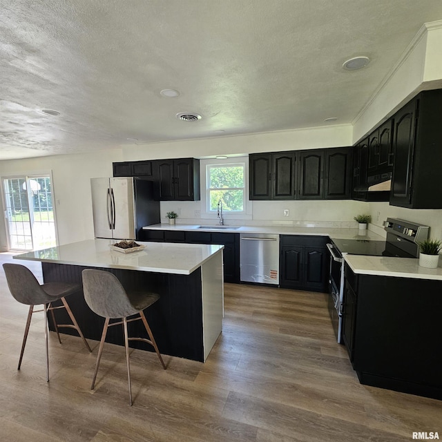 15074 N Mccauley Ln, Mount Vernon, IL 62864 - kitchen with appliances with stainless steel finishes, a sink, a textured ceiling, a breakfast bar, and a kitchen island