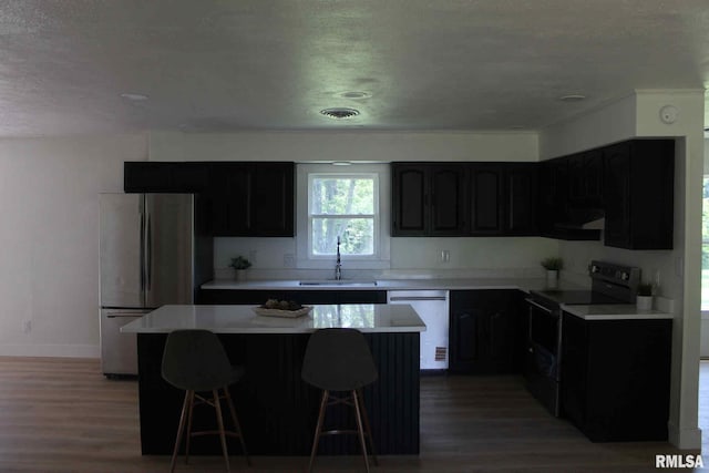 15074 N Mccauley Ln, Mount Vernon, IL 62864 - kitchen with appliances with stainless steel finishes, a sink, a textured ceiling, light wood-style flooring, and a kitchen island