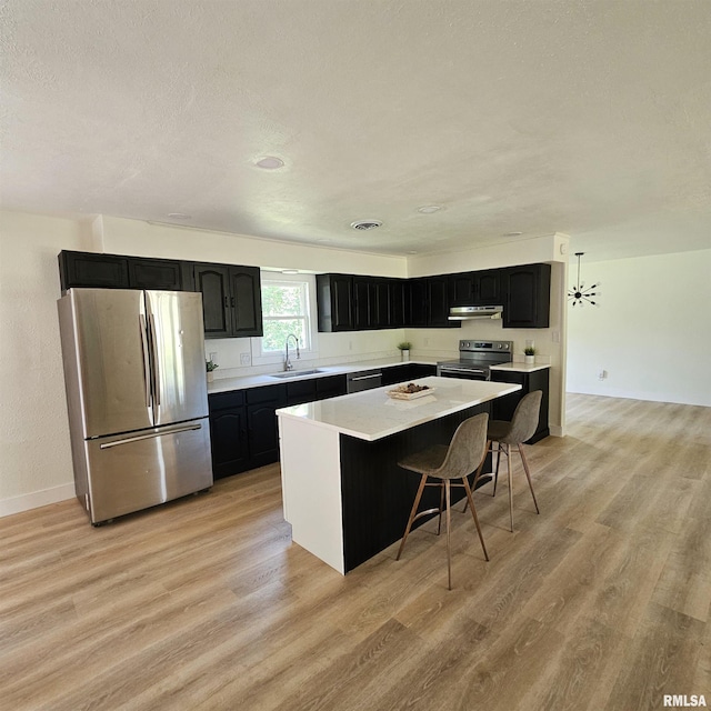 15074 N Mccauley Ln, Mount Vernon, IL 62864 - kitchen featuring appliances with stainless steel finishes, under cabinet range hood, a center island, light wood-style floors, and a textured ceiling