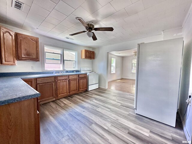 329 N Broadway Ave, Goreville, IL 62939 - kitchen with white appliances, ceiling fan, brown cabinets, and light wood finished floors