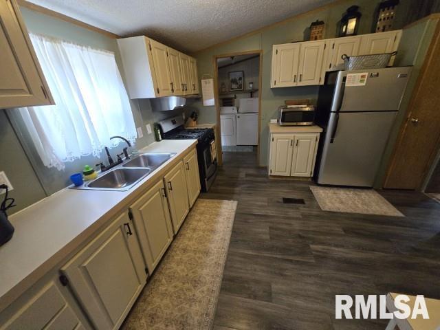 18802 E Fairfield Rd, Mount Vernon, IL 62864 - kitchen with stainless steel appliances, washer and dryer, vaulted ceiling, a textured ceiling, and dark wood-style floors