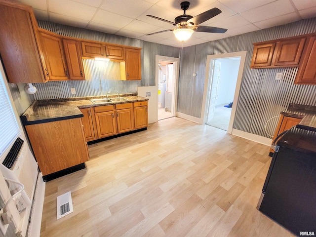 719 E Cherry St, Olney, IL 62450 - kitchen with a paneled ceiling, ceiling fan, brown cabinetry, light wood finished floors, and dark countertops
