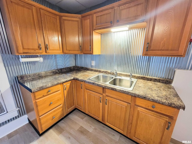 719 E Cherry St, Olney, IL 62450 - kitchen featuring brown cabinets, light wood-type flooring, wallpapered walls, and dark countertops