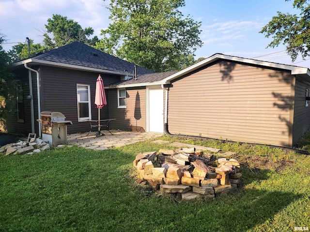 719 E Cherry St, Olney, IL 62450 - back of property featuring a fire pit, a patio, a lawn, and a shingled roof