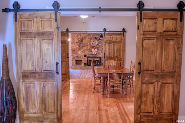 2036 Spruce St, Murphysboro, IL 62966 - dining room with a barn door, light wood-style floors, ceiling fan, and a stone fireplace