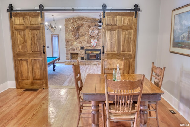 2036 Spruce St, Murphysboro, IL 62966 - dining room featuring a barn door, light wood-style floors, billiards table, and a stone fireplace