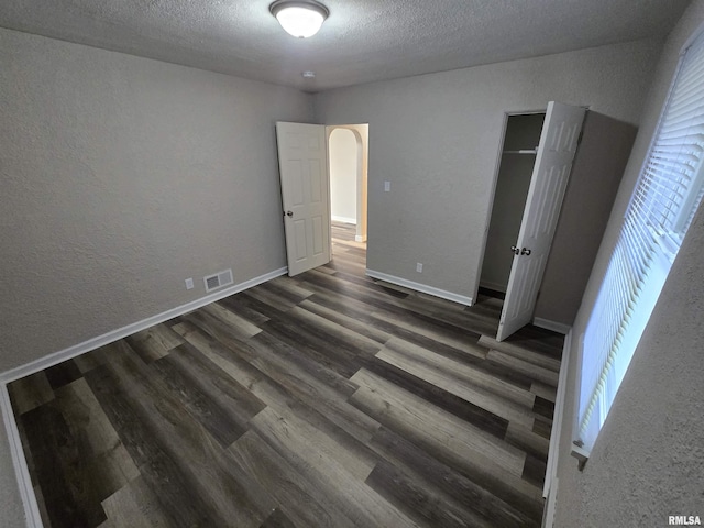 832 Fairfield Rd, Mount Vernon, IL 62864 - unfurnished bedroom with a textured wall, wood finished floors, a textured ceiling, arched walkways, and a closet
