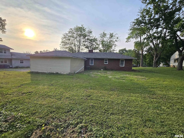 832 Fairfield Rd, Mount Vernon, IL 62864 - back of house at dusk featuring a chimney and a yard