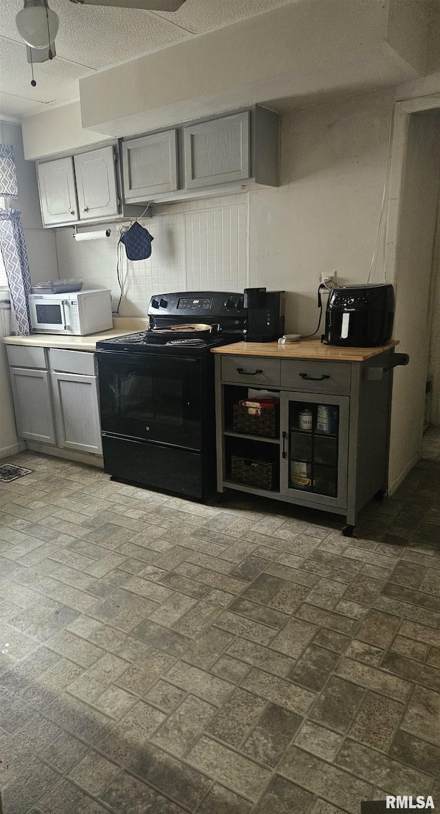 123 W College St, Harrisburg, IL 62946 - kitchen with black electric range oven, gray cabinetry, and brick patterned flooring