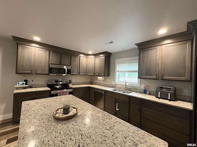 408 Madison St, Cambria, IL 62915 - kitchen featuring stainless steel appliances, dark brown cabinets, wood finished floors, light stone counters, and recessed lighting
