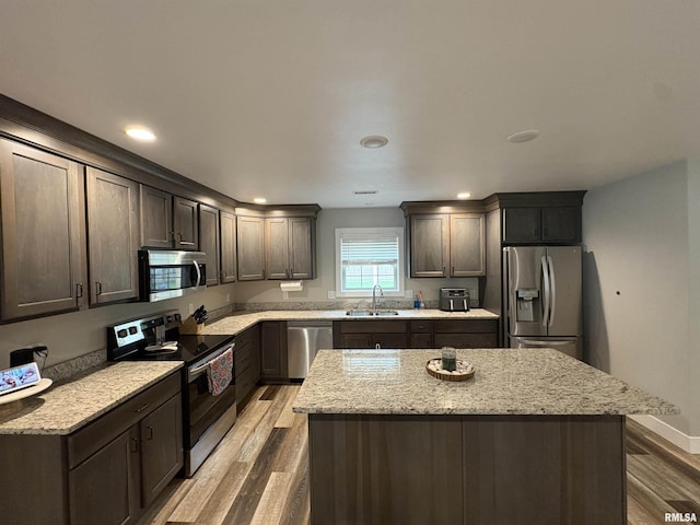 408 Madison St, Cambria, IL 62915 - kitchen featuring appliances with stainless steel finishes, wood finished floors, a kitchen island, dark brown cabinetry, and light stone countertops