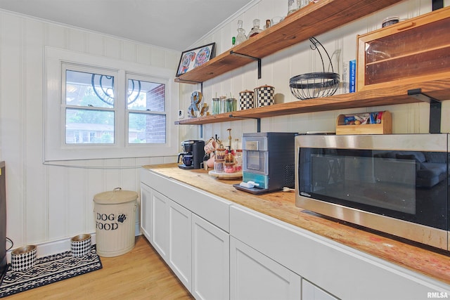 809 Dogwood Ln, Marion, IL 62959 - kitchen with stainless steel microwave, open shelves, crown molding, light countertops, and light wood finished floors