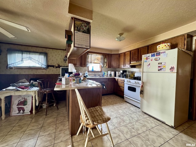 606 N Orchard St, West Frankfort, IL 62896 - kitchen featuring white appliances, under cabinet range hood, a textured ceiling, wallpapered walls, and a peninsula