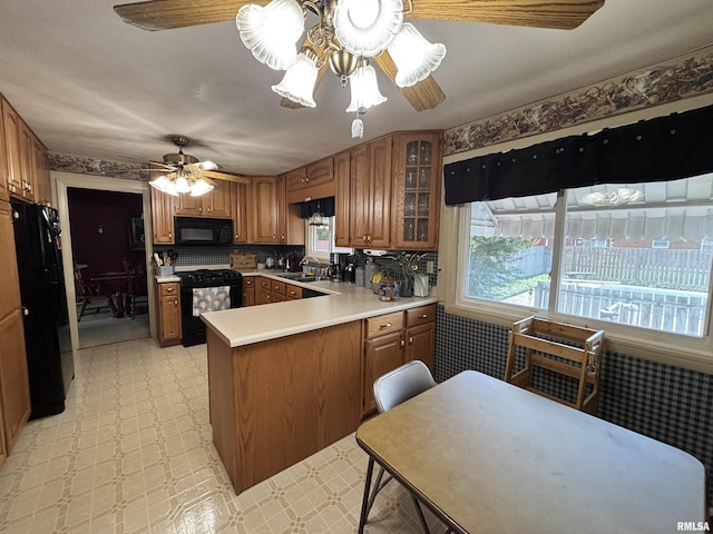 49 Jon St, Metropolis, IL 62960 - kitchen featuring black appliances, a peninsula, brown cabinetry, and plenty of natural light