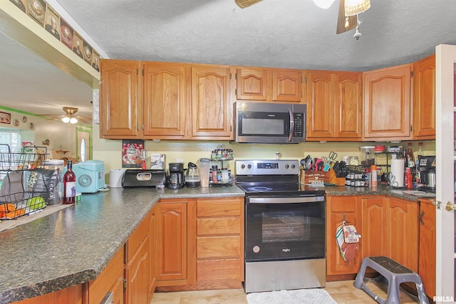 735 Sharp Rd, Anna, IL 62906 - kitchen with appliances with stainless steel finishes, ceiling fan, dark countertops, a peninsula, and brown cabinetry