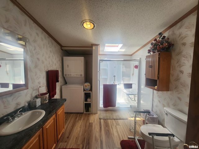 8747 Old State Route 14th Rte, Duquoin, IL 62832 - full bath with wallpapered walls, stacked washer / dryer, ornamental molding, a textured ceiling, and wood finished floors