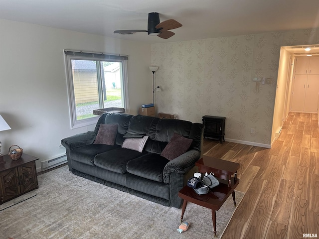 308 Blossom St, Carterville, IL 62918 - living area featuring wood finished floors, a baseboard radiator, ceiling fan, and a wood stove