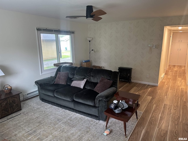 308 Blossom St, Carterville, IL 62918 - living area featuring wood finished floors, a baseboard heating unit, a ceiling fan, and a wood stove