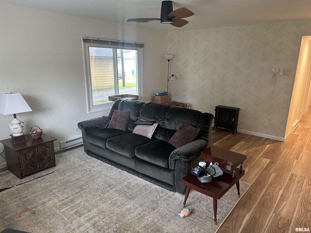 308 Blossom St, Carterville, IL 62918 - living area with wood finished floors, a baseboard heating unit, a wood stove, and a ceiling fan