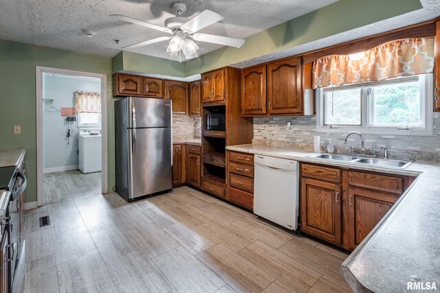 16777 Dublin St, West Frankfort, IL 62896 - kitchen featuring freestanding refrigerator, white dishwasher, washer / clothes dryer, brown cabinets, and decorative backsplash