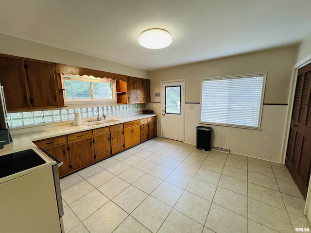 385 3rd St, Omaha, IL 62871 - kitchen with white electric range oven, light countertops, wainscoting, light tile patterned floors, and brown cabinets