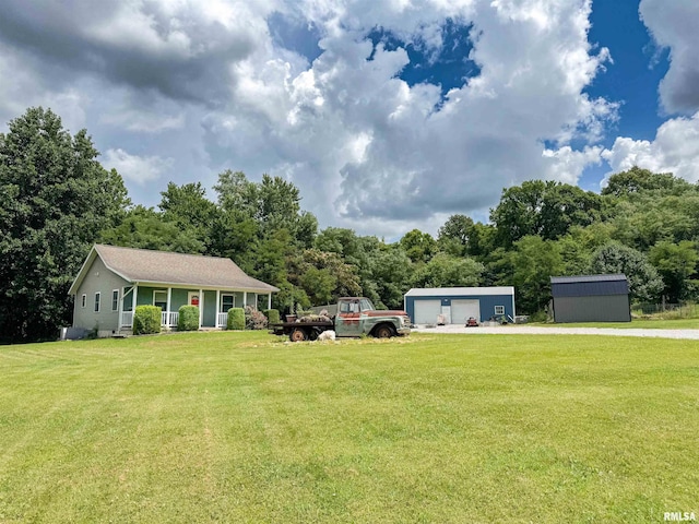 339 Spring St, Dongola, IL 62926 - view of front facade featuring a porch, a garage, an outbuilding, and a front lawn
