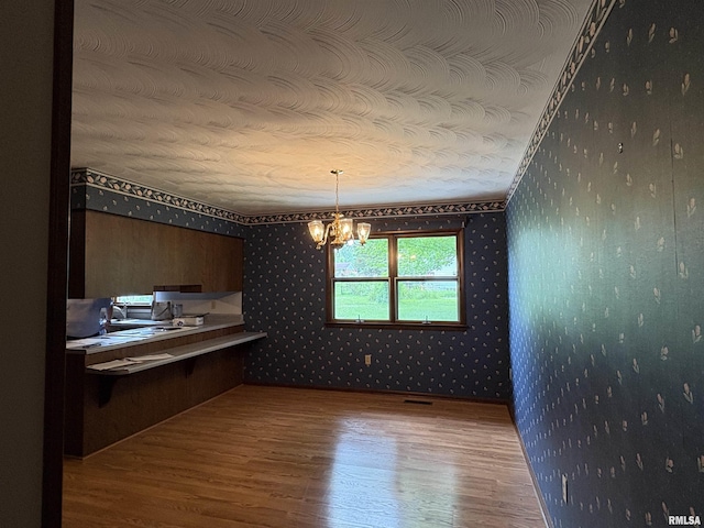 822 N 24th St, Murphysboro, IL 62966 - unfurnished dining area with wallpapered walls, wood finished floors, a chandelier, an office area, and a textured ceiling