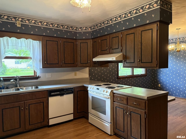 822 N 24th St, Murphysboro, IL 62966 - kitchen featuring white appliances, under cabinet range hood, light wood-style flooring, wallpapered walls, and a chandelier