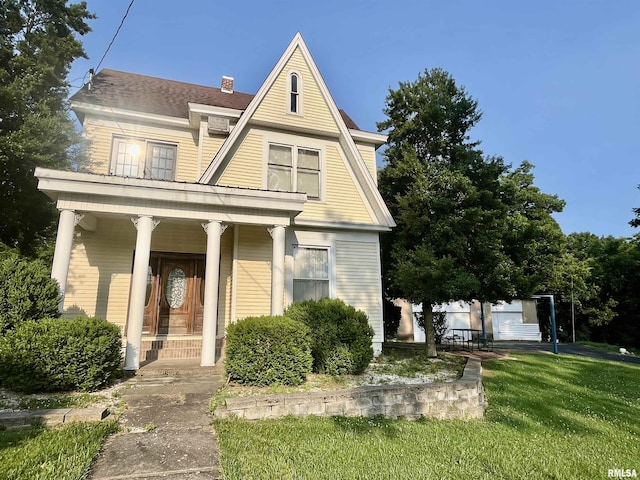 850 Joppa N Ave, Joppa, IL 62953 - view of front of property with covered porch, a front yard, a shingled roof, and a chimney