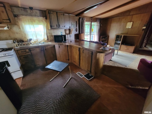 1060 W 5th St, Flora, IL 62839 - kitchen with white gas range oven, black microwave, a peninsula, range hood, and wooden walls